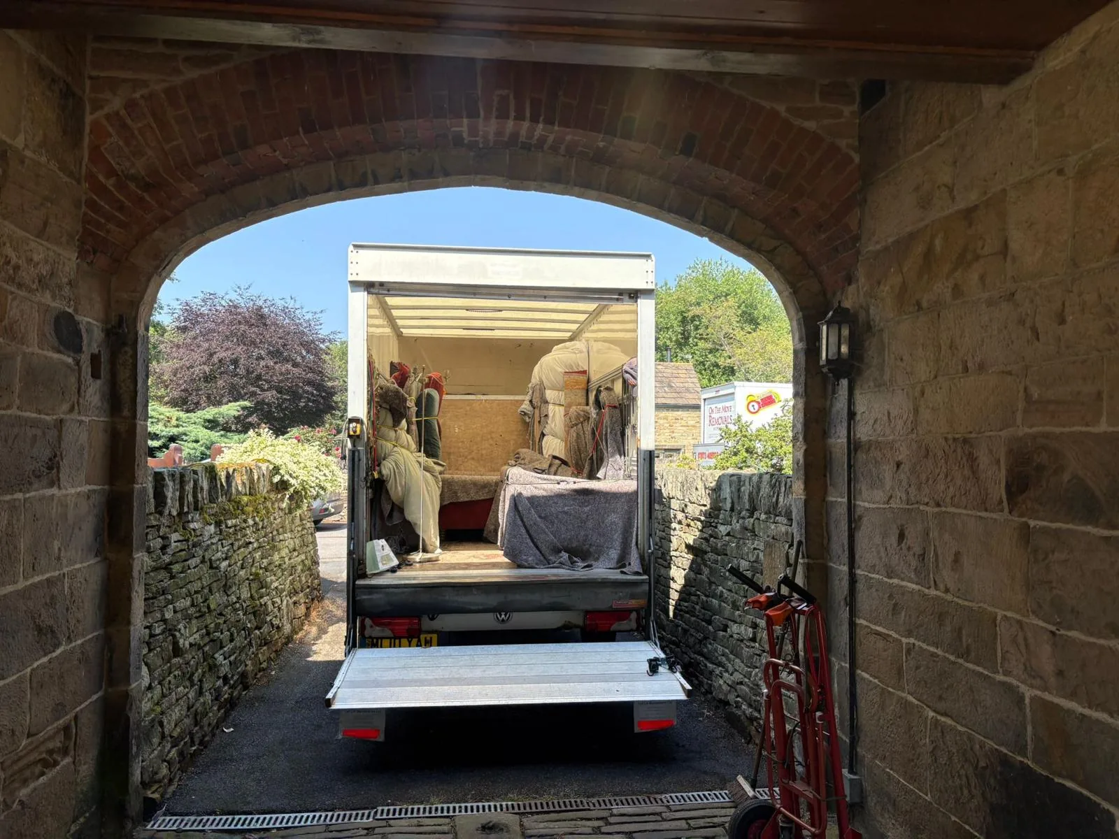 Removal van loaded with protected furniture under a stone archway by On The Move Removals in Rastrick
