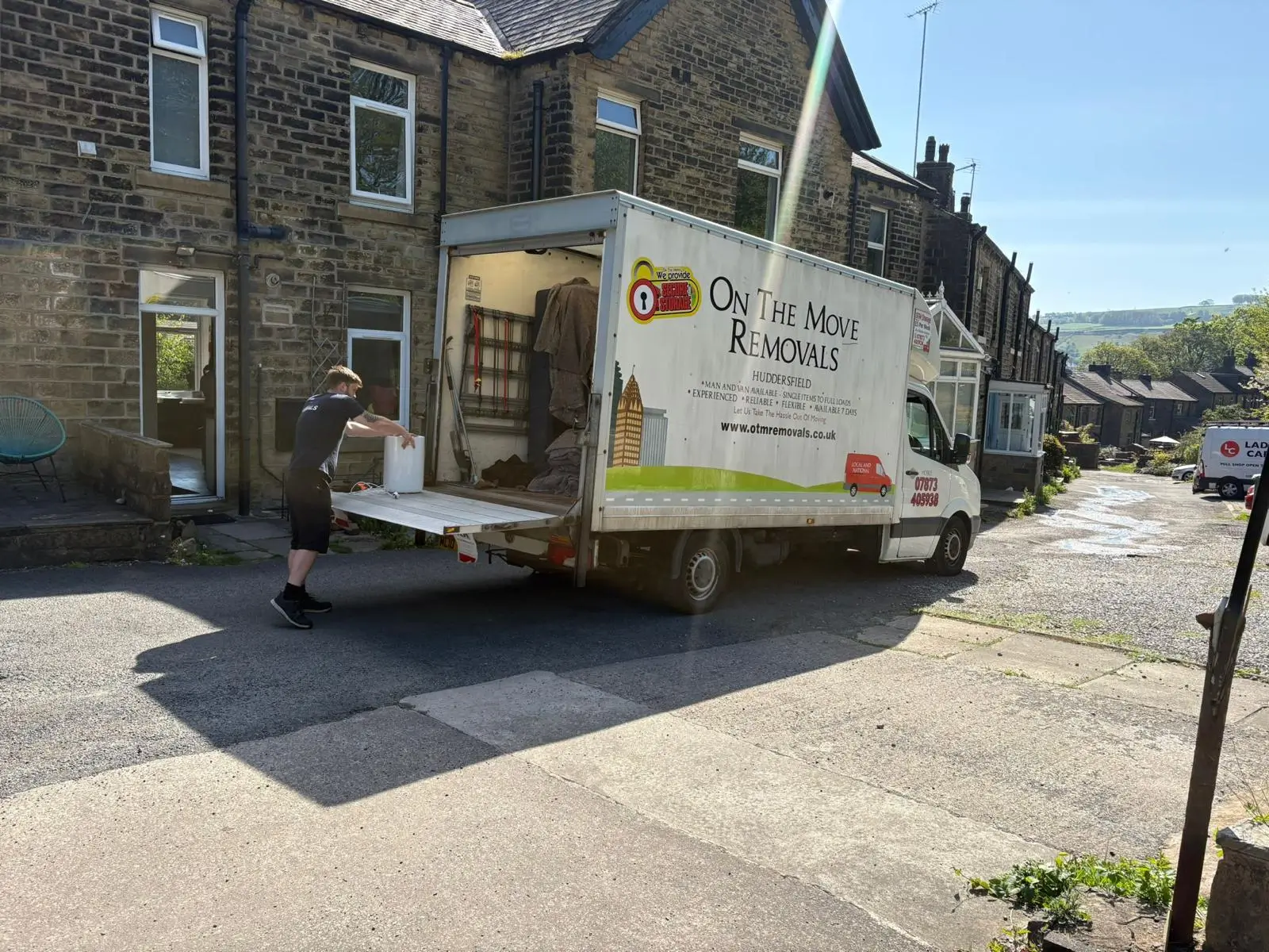 On The Move Removals team member carrying a packed box from the back of the van during a Huddersfield house move